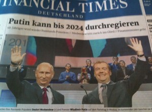 A newspaper front page with the headline "Putin kann bis 2024 durchregieren" from the Financial Times Deutschland. The image shows two men in suits, one on the left and one on the right, both raising their hands and smiling. There are several people in the background. The text below the image mentions the names "Dmitri Medwedew" and "Wladimir Putin."