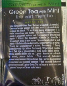 The image shows a packet of green tea with mint. The front of the packet has text in multiple languages, including English, French, and others. The English text reads "Green Tea with Mint" and "Mint Flavoured Green Tea." There are also icons at the bottom of the packet, which likely represent instructions or certifications. The packet has a green and black color scheme.