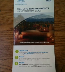 Alt text: A promotional flyer for Marriott Rewards and Visa offering up to two free nights using a Visa card. The flyer includes an image of a luxurious outdoor seating area with a pool and scenic view. The text outlines three steps to earn the free nights: 1) Register online or call a provided number, 2) Stay at participating hotels between specified dates, and 3) Earn one free night after every second stay, up to two free nights. The website MarriottRewards.com/MegaBonus is also mentioned.