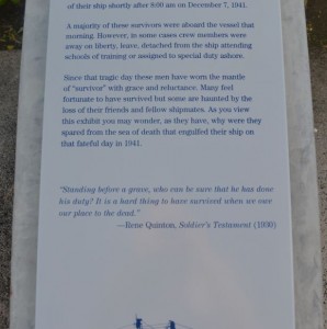 The image shows a memorial plaque with an inscription. The text on the plaque reads:

"A majority of these survivors were aboard the vessel that morning. However, in some cases crew members were away on liberty, leave, detached from the ship attending schools of training or assigned to special duty ashore.

Since that tragic day these men have worn the mantle of 'survivor' with grace and reluctance. Many feel fortunate to have survived but some are haunted by the loss of their friends and fellow shipmates. As you view this exhibit you may wonder, as they have, why were they spared from the sea of death that engulfed their ship on that fateful day in 1941.

'Standing before a grave, who can be sure that he has done his duty? It is a hard thing to have survived when we see our place to the dead.'
— Rene Quinton, Soldier's Testament (1920)"

The plaque is mounted on a stone base and is located outdoors.