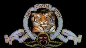 The image shows a parody of the MGM (Metro-Goldwyn-Mayer) logo. Instead of the traditional lion, there is a tiger in the center of the logo. The surrounding elements, including the Latin phrase "Ars Gratia Artis" (Art for Art's Sake) and the film reel design, remain the same. The background is black.