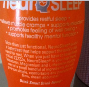 The image shows the back of a bottle of NeuroSleep, a beverage. The text on the bottle highlights the benefits of the drink, stating that it provides restful sleep, relieves muscle cramps, supports relaxation, promotes a feeling of well-being, and supports healthy mental function. The text further explains that NeuroSleep is a tasty treat that helps support the body’s need for rest, containing ingredients like Melatonin, Magnesium, and L-Theanine. The slogan at the bottom reads, "Drink Smart Drink Neuro."