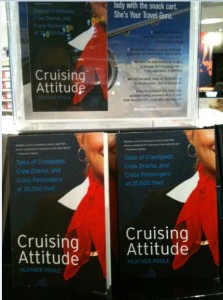 The image shows a display of books titled "Cruising Attitude" by Heather Poole. The cover features a close-up of a person wearing a red scarf and a white shirt. The subtitle reads, "Tales of Crashpads, Crew Drama, and Crazy Passengers at 35,000 Feet." There are multiple copies of the book arranged on a shelf, with a promotional sign above them.