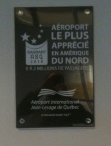 The image shows a plaque awarded to Aéroport international Jean-Lesage de Québec. The text on the plaque is in French and reads:

"AÉROPORT LE PLUS APPRÉCIÉ EN AMÉRIQUE DU NORD
GAGNANT ASQ 2010
0 À 2 MILLIONS DE PASSAGERS

Aéroport international Jean-Lesage de Québec
LE PASSAGER AVANT TOUT"

Translation:
"THE MOST APPRECIATED AIRPORT IN NORTH AMERICA
WINNER ASQ 2010
0 TO 2 MILLION PASSENGERS

Jean-Lesage International Airport of Quebec
THE PASSENGER FIRST"