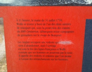 The image shows a red informational plaque with French text. The text describes a historical event that took place on the morning of July 31, 1759, involving Wolfe and the landing of grenadiers on the beach of Beauport under the protection of the cannons of the HMS Centurion. The English occupied a redoubt that was abandoned, and Wolfe ordered his men to attack the entrenchments on the heights.