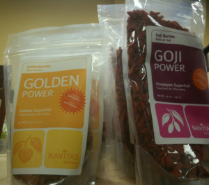 The image shows two packages of dried superfruits from the brand Navitas Naturals. The package on the left is labeled "Golden Power" and contains goldenberries, described as an Andean superfruit. The package on the right is labeled "Goji Power" and contains goji berries, described as a Himalayan superfruit. Both packages are clear with colorful labels, allowing the dried fruits inside to be visible.