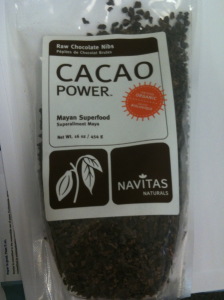 The image shows a package of "Cacao Power" raw chocolate nibs by Navitas Naturals. The package is labeled as "Mayan Superfood" and contains 16 ounces (454 grams) of the product. The packaging is clear, allowing the cacao nibs to be visible inside. The label also mentions that the product is organic.